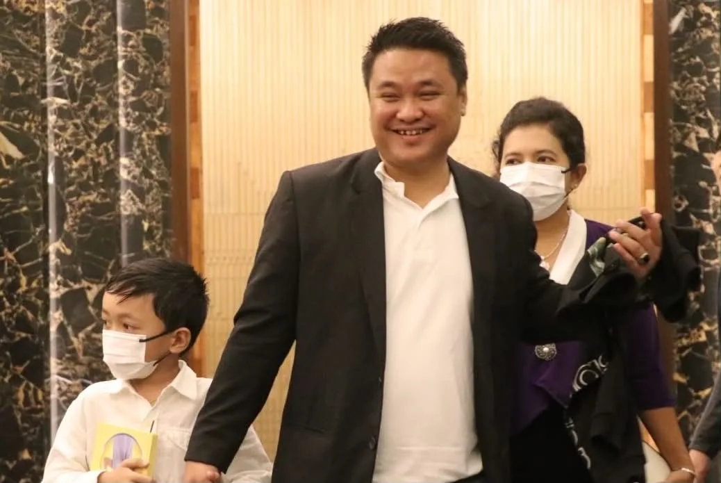 Man with a child and woman at an indoor gathering