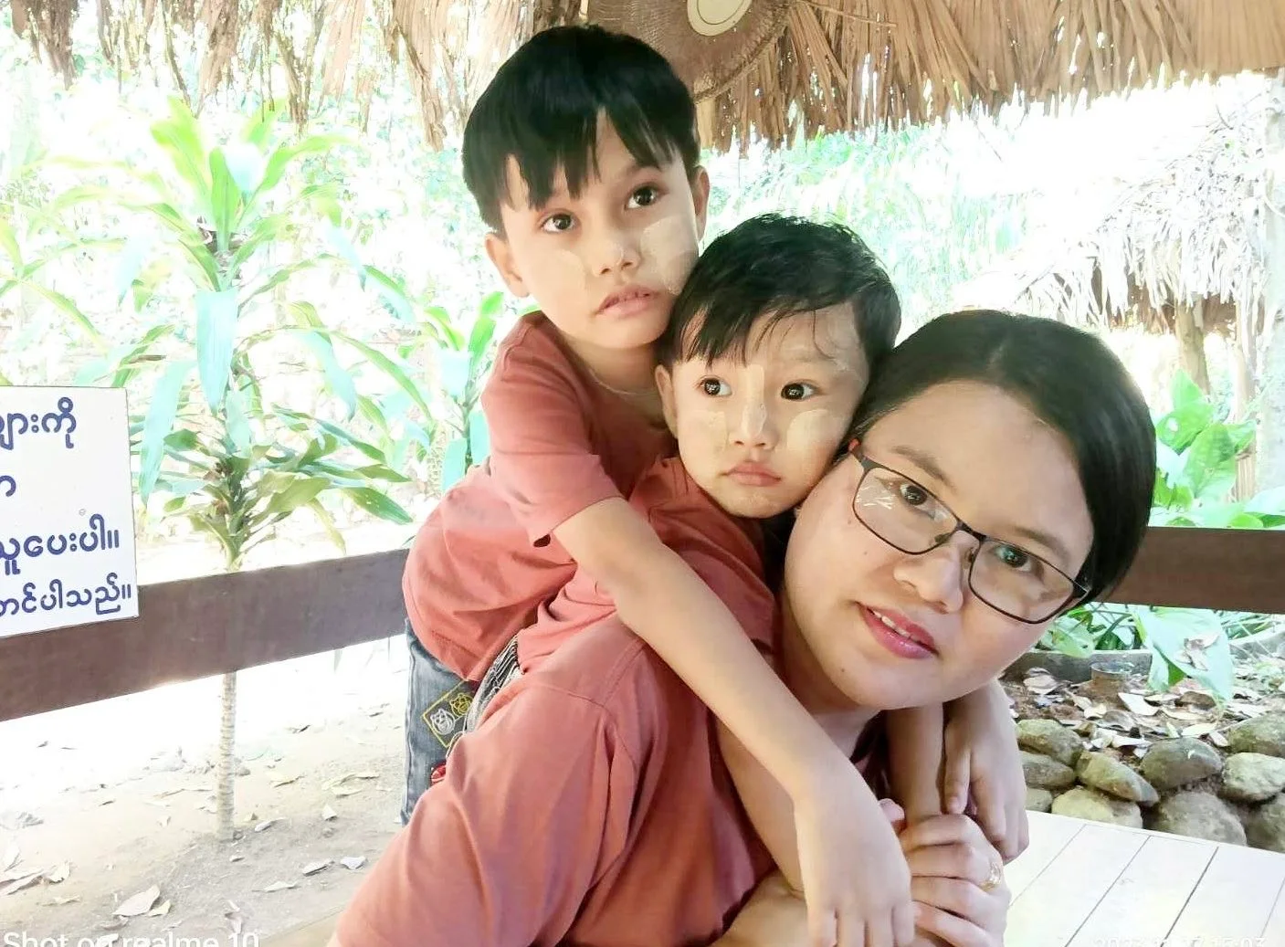 Woman with two children under a thatched roof