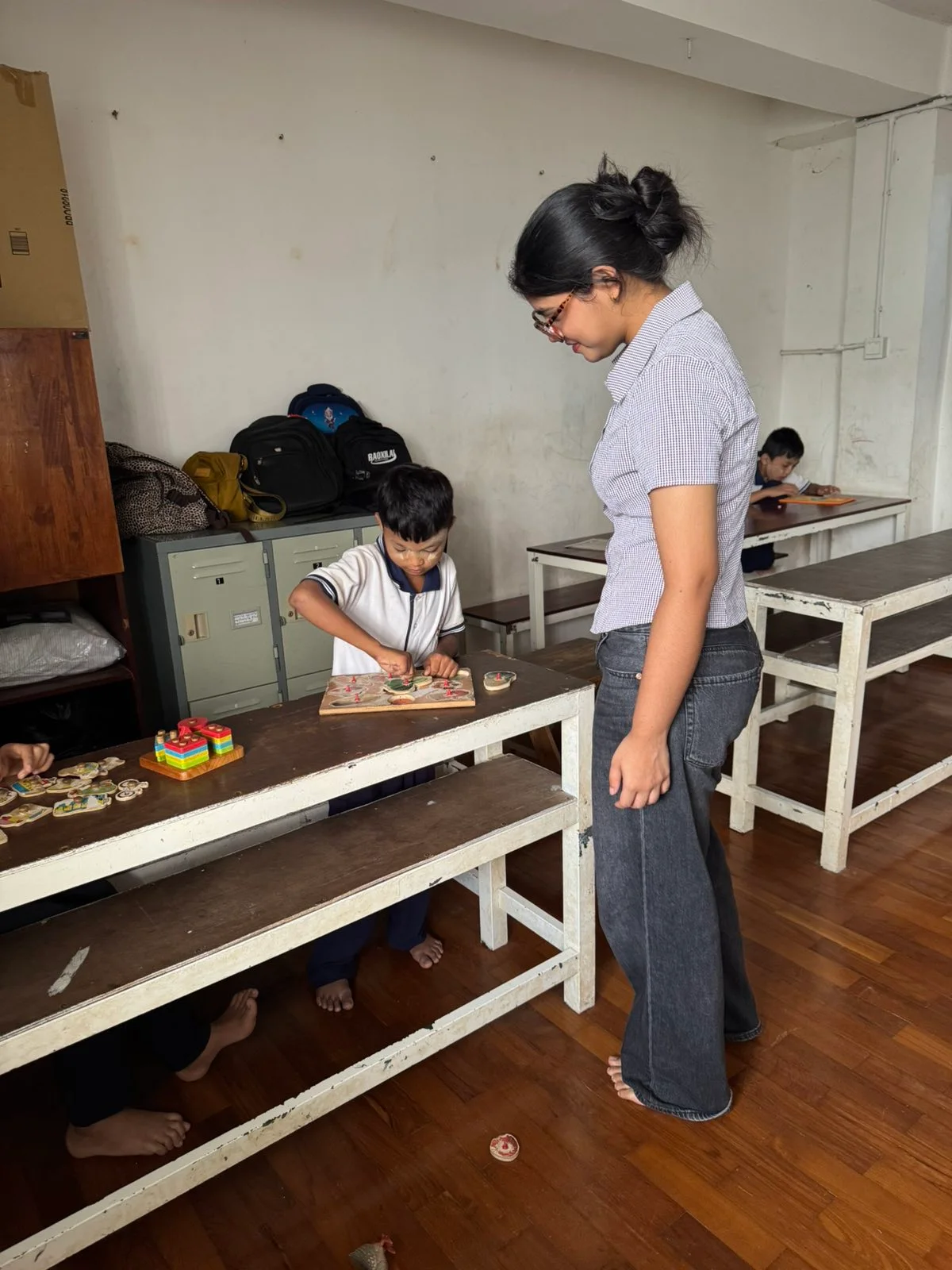 Volunteer supporting a child with a learning activity in a classroom