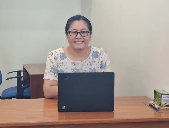 Woman smiling behind a laptop at a desk